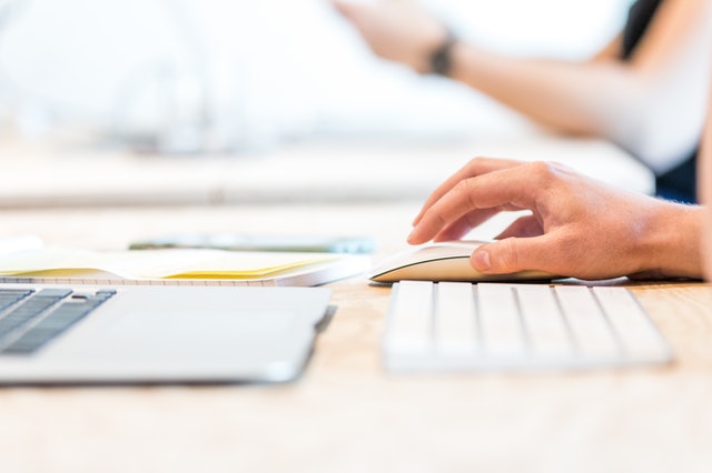 a  hand on a mouse while working on a computer